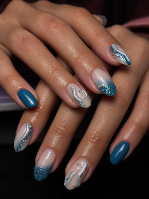 Ongles amande bleu pétrole et nude, vagues argentées en relief, paillettes et petits strass